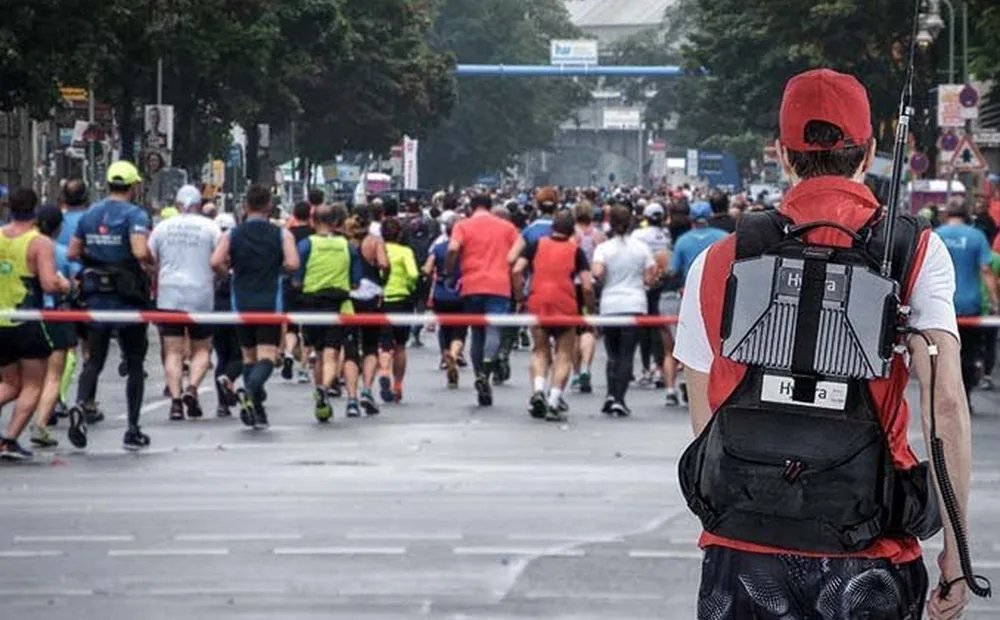 Event marshal carrying a portable radio repeater at a mass participation road event